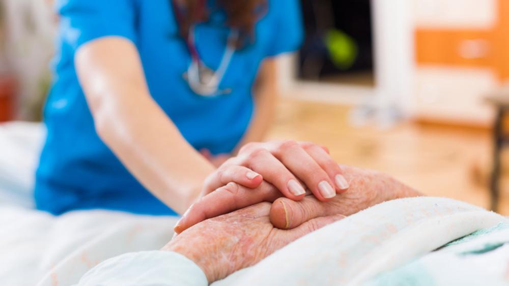 Nurse touching patient's hands